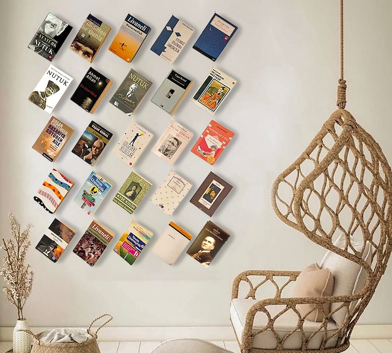 May include: A collection of books with various covers, including titles like "NUTUK" and "Bir Deniz", are displayed on a wall. A woven hanging chair is visible on the right side of the image, creating a cozy reading nook.