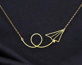 May include: A gold necklace with a paper airplane pendant. The airplane is flying in a loop.