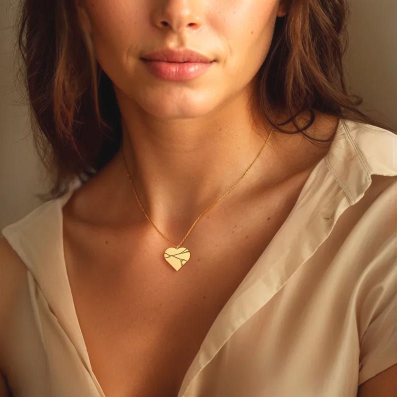 Peut inclure: Un collier avec un pendentif en forme de c&oelig;ur dor&eacute;. Le pendentif en forme de c&oelig;ur pr&eacute;sente une surface textur&eacute;e avec de fines lignes entrecrois&eacute;es. Le collier est port&eacute; par une personne, et la cha&icirc;ne est d&eacute;licate et dor&eacute;e.