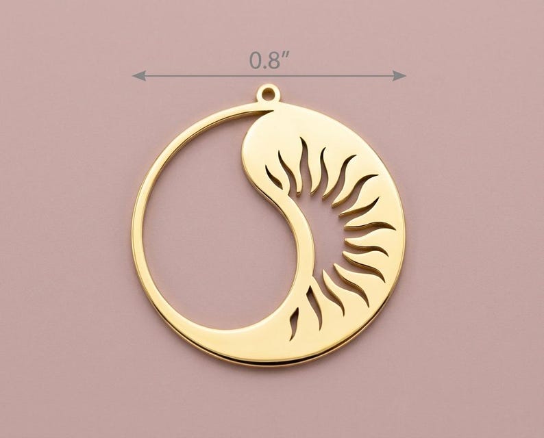 May include: A gold-colored pendant with a sun and moon design. The pendant is approximately 0.8 inches in diameter. The sun is represented by a series of cut-out rays, and the moon is a curved shape. The pendant has a small loop at the top for hanging.