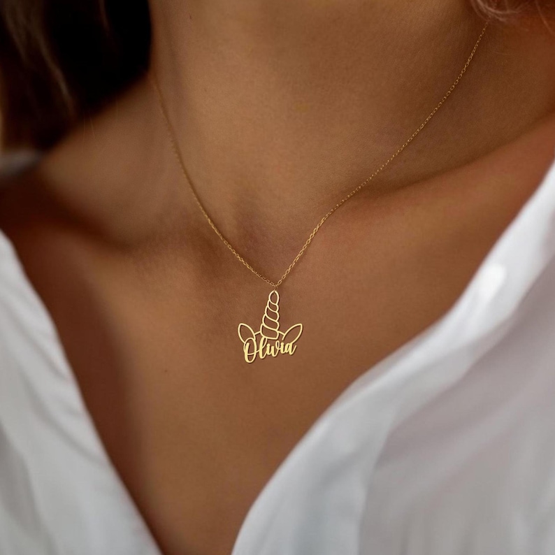 Peut inclure: Collier en or avec un pendentif en forme de licorne avec le nom Olivia. Le pendentif est un contour d&eacute;licat d'une t&ecirc;te de licorne avec une corne et des oreilles.