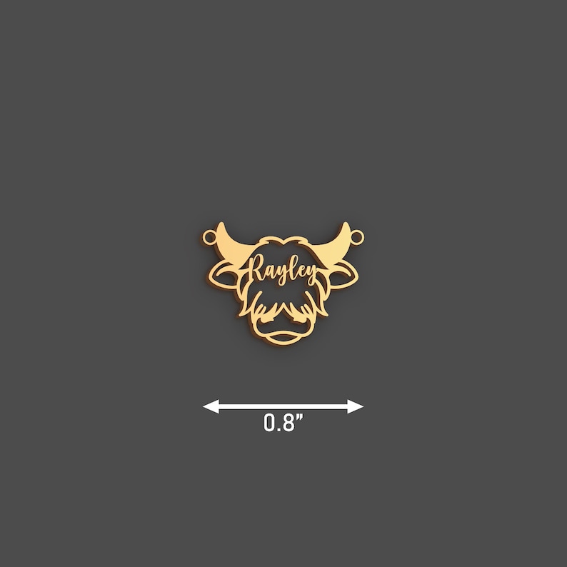 May include: A gold-colored pendant in the shape of a Highland cow head, measuring 0.8 inches across. The name "Rayley" is inscribed in a script font across the face of the cow. The pendant has two small loops for attaching to a chain.