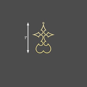 Puede incluir: Un colgante dorado con un dise&ntilde;o calado decorativo. El colgante mide aproximadamente 2,5 cm de altura y presenta una forma de cruz estilizada con curvas intrincadas y un peque&ntilde;o lazo en la parte superior para colgar. El fondo es gris oscuro.