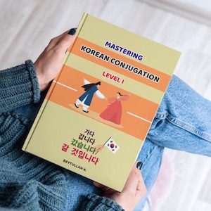 Op de afbeelding: Een softcover boek getiteld Mastering Korean Conjugation Level 1 met een lichtgele kaft. De kaft bevat een illustratie van twee figuren in traditionele kleding, een kleine Zuid-Koreaanse vlag en Koreaanse tekst, waaronder 가다, 갑니다, 갔습니다 en 갈 것입니다.