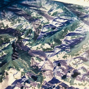 May include: A detailed map of the Bighorn Crags area in Wyoming, showing various trails, lakes, and mountains. The map features a blue and green color scheme with contour lines indicating elevation changes.