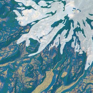 May include: An aerial view of a snow-capped mountain with a large crater at the top. The mountain is surrounded by green and blue terrain.