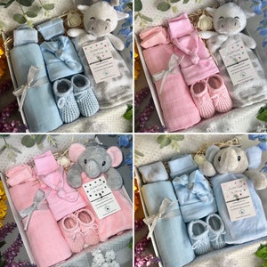 May include: Four gift boxes filled with baby items. Each box contains a plush animal, a blanket, a hat, a pair of socks, and a pair of booties. The boxes are decorated with ribbons and bows. The plush animals are a giraffe, an elephant, a giraffe, and an elephant. The blankets are blue, pink, blue, and pink. The hats are blue, pink, blue, and pink. The socks are blue, pink, blue, and pink. The booties are blue, pink, blue, and pink.