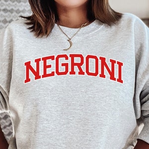 May include: A gray sweatshirt with the word "NEGRONI" printed in red on the front.