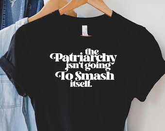 Puede incluir: Camiseta negra con texto blanco que dice "the Patriarchy isn't going to Smash itself."