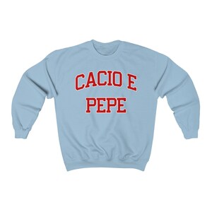 Puede incluir: Sudadera azul claro con el texto "Cacio e Pepe" en rojo.