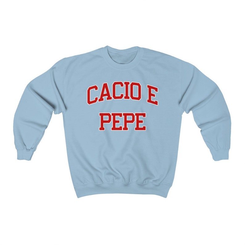 Puede incluir: Sudadera azul claro con el texto "Cacio e Pepe" en rojo.