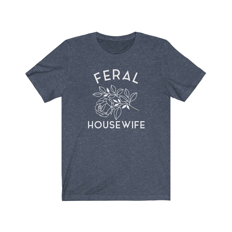 May include: A dark blue t-shirt with the text "FERAL HOUSEWIFE" in white lettering. A white outline of a rose with leaves is above the text.