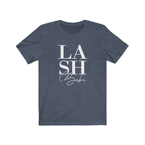 Pu&ograve; includere: T-shirt blu navy con la scritta bianca "LASH Babe". La parola "LASH" &egrave; sovrapposta a "SH", e "Babe" &egrave; scritta in corsivo sotto. La maglietta &egrave; realizzata in un materiale morbido.