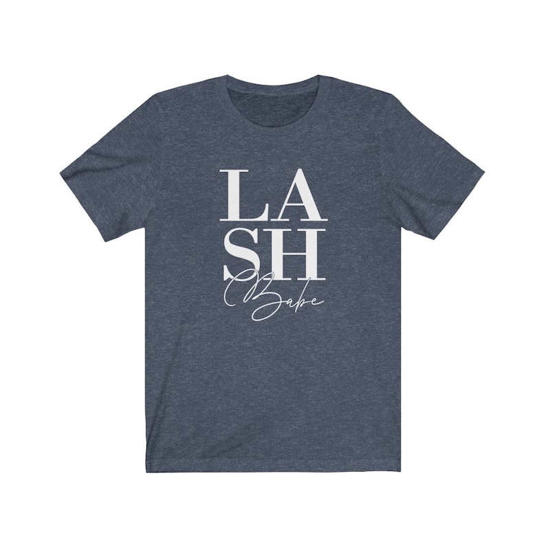 Pu&ograve; includere: T-shirt blu navy con la scritta bianca "LASH Babe". La parola "LASH" &egrave; sovrapposta a "SH", e "Babe" &egrave; scritta in corsivo sotto. La maglietta &egrave; realizzata in un materiale morbido.
