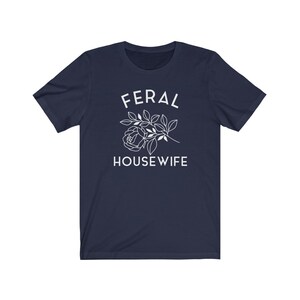 May include: Navy blue t-shirt with white text that reads "FERAL HOUSEWIFE" and a stylized white rose with leaves.