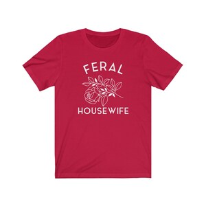 May include: Red short-sleeved t-shirt with white text that reads "FERAL HOUSEWIFE" and a stylized white rose.