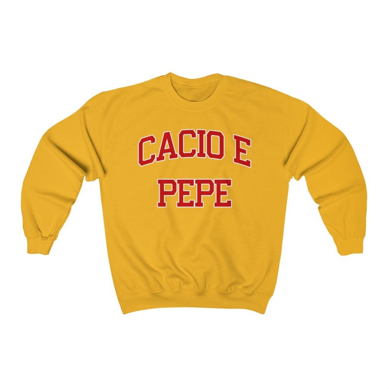 Puede incluir: Una sudadera amarilla con el texto "Cacio e Pepe" en rojo.