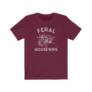 May include: Burgundy t-shirt with white text that reads "Feral Housewife" and a stylized white rose with leaves.