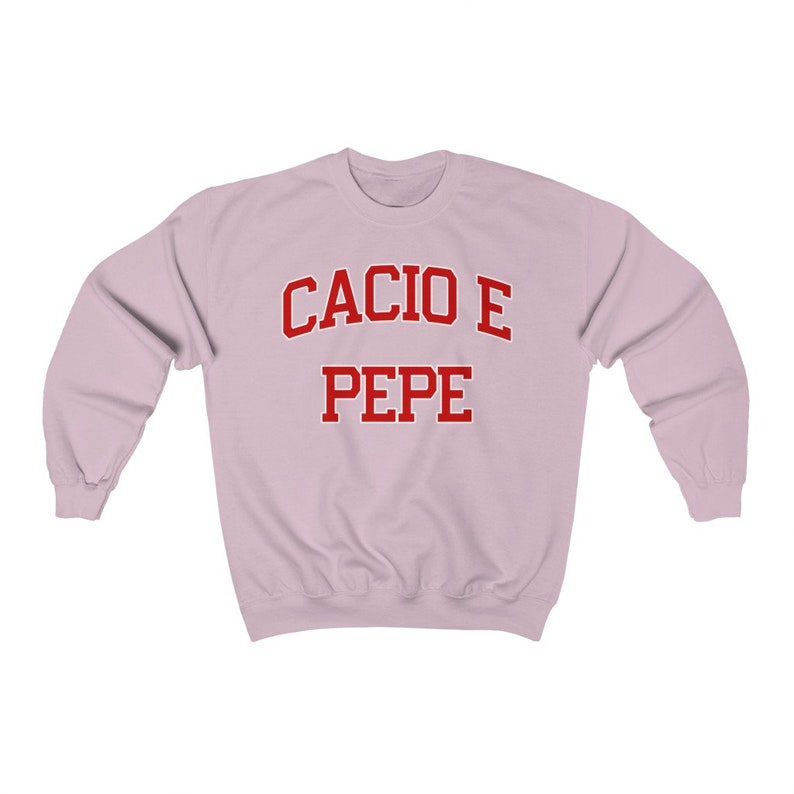 Puede incluir: Una sudadera de color rosa claro con el texto "Cacio e Pepe" en rojo.