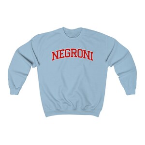 May include: A light blue sweatshirt with the word "NEGRONI" printed in red on the front.