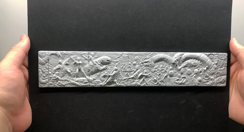 May include: A white, 3D printed wall sculpture depicting a scene from a science fiction movie. The sculpture is divided into five sections, each showing a different part of the scene. The scene includes a large, alien creature, a group of human characters, and a spaceship.