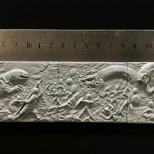May include: A white, three-dimensional relief sculpture depicting a scene of a battle between humans and a large, serpentine creature. The sculpture is divided into four sections, each depicting a different part of the battle. The sculpture is made of plaster or a similar material.