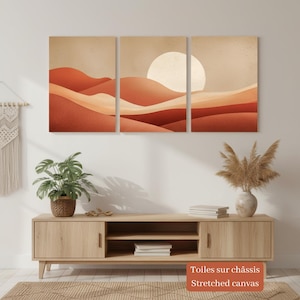Può includere: Un set di tre quadri che raffigura un paesaggio desertico con dune di sabbia in tonalità terracotta, arancione bruciato e crema. Un grande sole circolare pallido è posizionato sul pannello centrale. L'opera è stampata su tela tesa.