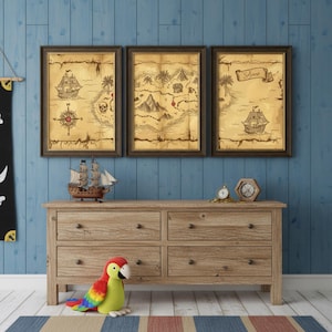May include: Three framed vintage-style pirate maps with ships, compasses, and treasure. A wooden dresser with a toy ship, clock, and parrot sits below the maps. The wall is blue.