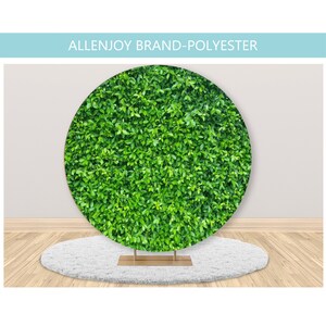 May include: A green leafy backdrop for photography, made of polyester fabric. The backdrop is circular and is displayed on a white fluffy rug.