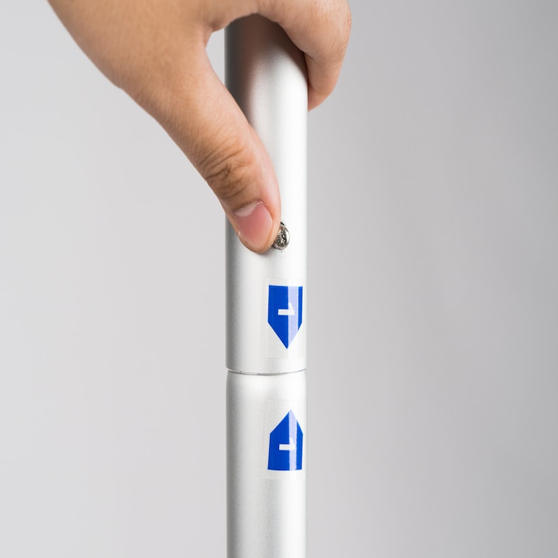 May include: A silver telescopic pole with a blue arrow pointing down and a blue arrow pointing up. The pole is being extended by a hand.
