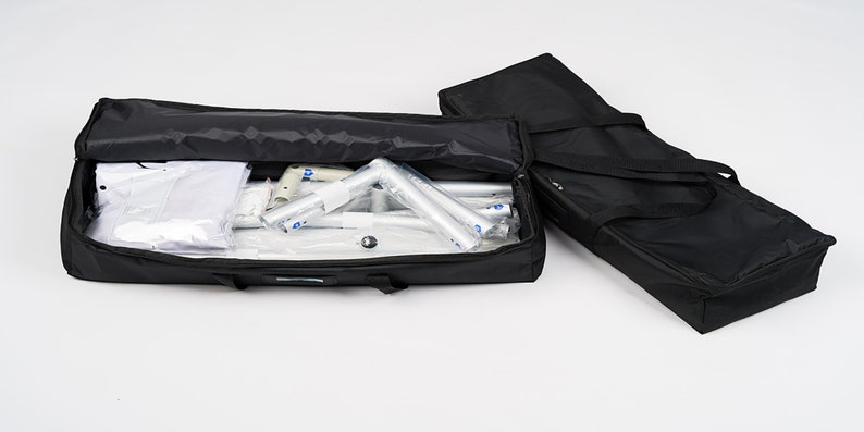 May include: Two black carrying cases with zippers and handles. One case is open and contains a white backdrop and silver poles.
