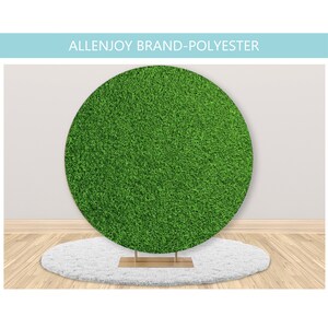 May include: A round green backdrop made of polyester fabric, resembling artificial grass. The backdrop is on a white fluffy rug and a gold stand.