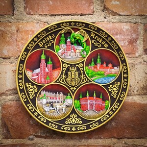 May include: A round, decorative plate with a gold frame and six sections. Each section features a different image of a city in Poland, including Krakow, with the name of the city and "Polska" written in gold lettering.