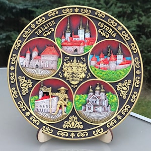May include: A round black and gold plate with a decorative border. The plate is divided into five sections, each featuring a different image of Tallinn, Estonia. The top section features the text "Tallinn Estonia".