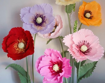 May include: A bouquet of six large paper poppies in various colors, including red, pink, purple, orange, and cream. The flowers have ruffled petals and are arranged in a vase.