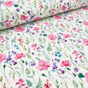 Könnte beinhalten: Weißer Stoff mit einem Aquarell-Blumenmuster. Das Design zeigt rosa Mohnblumen, violette Glockenblumen, blaue Vergissmeinnicht und grünes Laub. Der Stoff ist gerollt und zeigt das sich wiederholende Muster.