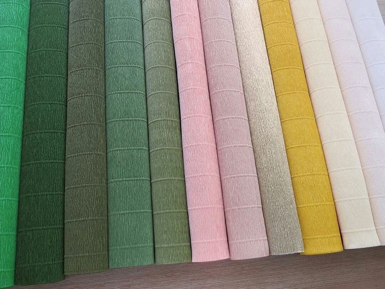 May include: Assortment of 12 rolls of crepe paper in various shades of green, pink, gold, and white. The paper has a textured, crinkled appearance.