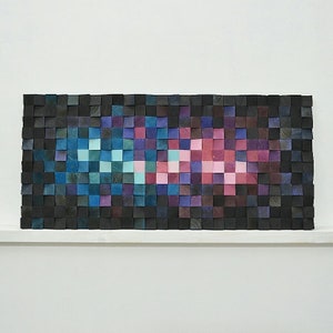 May include: Abstract wall art made of wood blocks in shades of black, blue, purple, pink, and teal. The blocks are arranged in a geometric pattern.