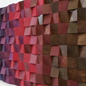 Könnte beinhalten: Ein Wandkunstwerk aus Holzblöcken in Violett-, Rot- und Brauntönen. Die Blöcke sind in einem versetzten Muster angeordnet, wodurch ein Verlaufseffekt entsteht.