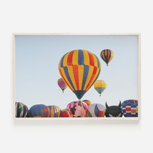 May include: A colorful group of hot air balloons in the sky, with a large blue and yellow striped balloon in the center.