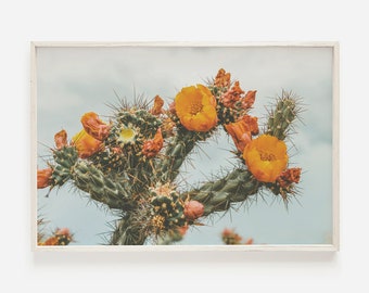 May include: A close-up of a prickly pear cactus in bloom with bright yellow flowers and orange buds against a light blue sky.