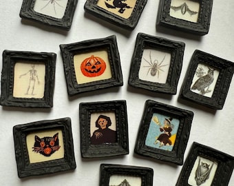 May include: A collection of twelve miniature black ornate frames containing various Halloween-themed illustrations, including a spider, a witch silhouette, a bat, a skeleton, a jack-o'-lantern, an owl, a black cat, a grim reaper, and a flying witch.