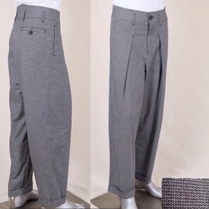 May include: Grey trousers with a checked pattern and pleats. The trousers have a cuffed hem and a button fly.