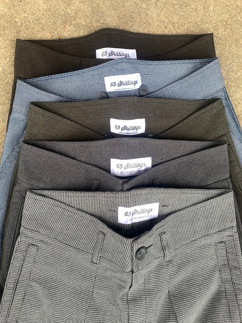May include: Five pairs of grey, black and blue trousers with a white label that says "65 Shillings" on each pair.