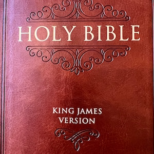 May include: A brown leather-bound Holy Bible with the text "HOLY BIBLE" in gold lettering. The cover features an ornate, embossed design. The words "KING JAMES VERSION" are also visible.