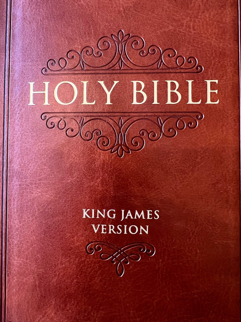 May include: A brown leather-bound Holy Bible with the text "HOLY BIBLE" in gold lettering. The cover features an ornate, embossed design. The words "KING JAMES VERSION" are also visible.