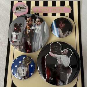 May include: A set of four round pinback buttons featuring Disney and Star Wars characters. One button shows Mickey and Minnie Mouse, another Luke Skywalker with a lightsaber, and a third Chewbacca hugging Princess Leia. The fourth button has R2-D2 and C-3PO.