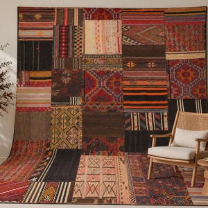 May include: A large rectangular area rug featuring a patchwork design composed of various woven textile segments in shades of red, orange, brown, black, and cream, displaying diverse geometric patterns, stripes, and intricate tribal-inspired motifs.