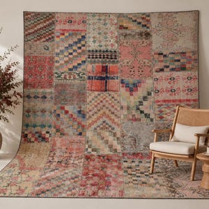 Könnte beinhalten: Ein großer rechteckiger Teppich mit einem Patchwork-Design, das aus verschiedenen Textilsegmenten in den Farben Rosa, Rot, Blau und Creme besteht. Der Teppich zeigt eine Mischung aus geometrischen Mustern, darunter Rauten, Streifen und Blumenmotive.