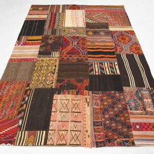 May include: A rectangular area rug composed of various stitched fabric patches featuring diverse geometric patterns and a multi-colored palette including shades of red, orange, yellow, brown, black, and cream in a woven textile construction.